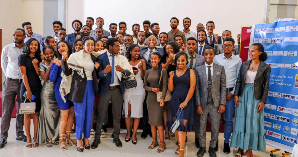 A large group of people, dressed formally, pose happily for a photo at an event related to logistics and supply chain.