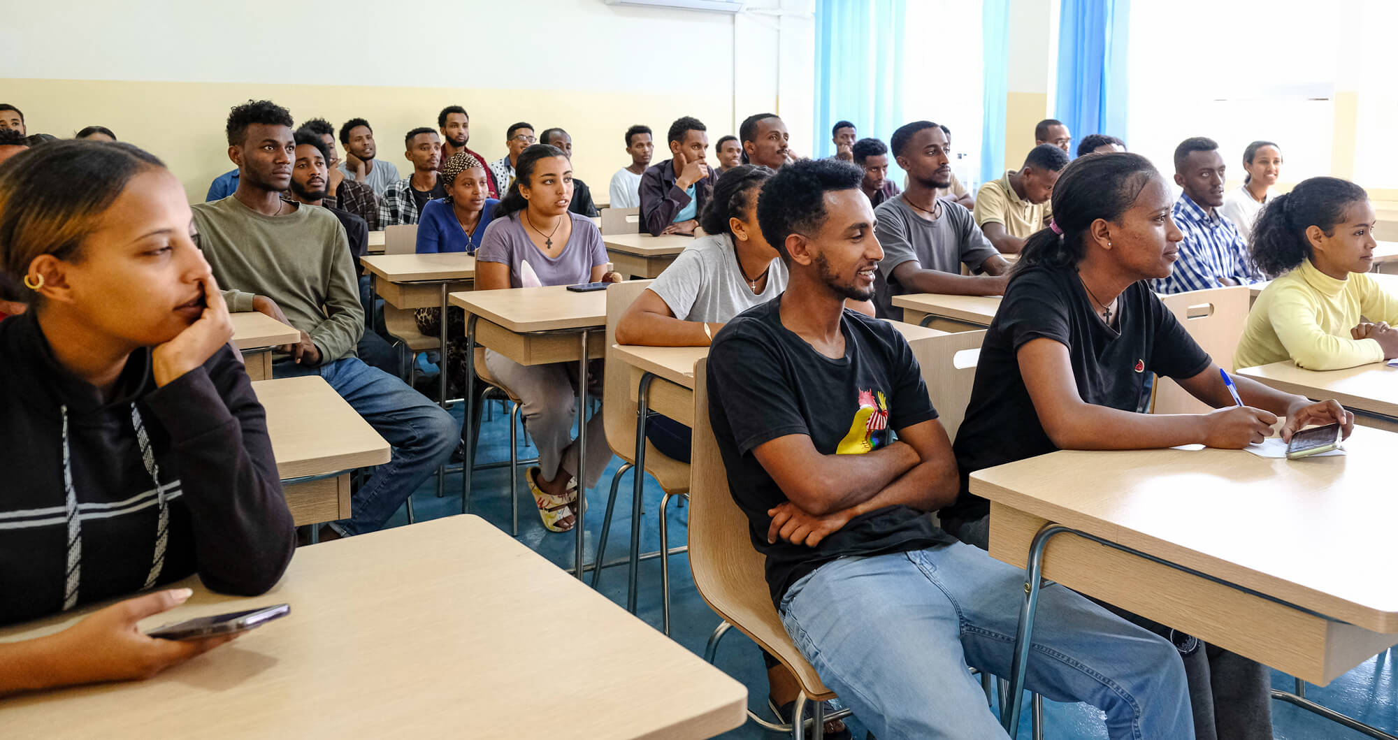 A group of students sitting attentively at desks in a classroom during a lecture or discussion.